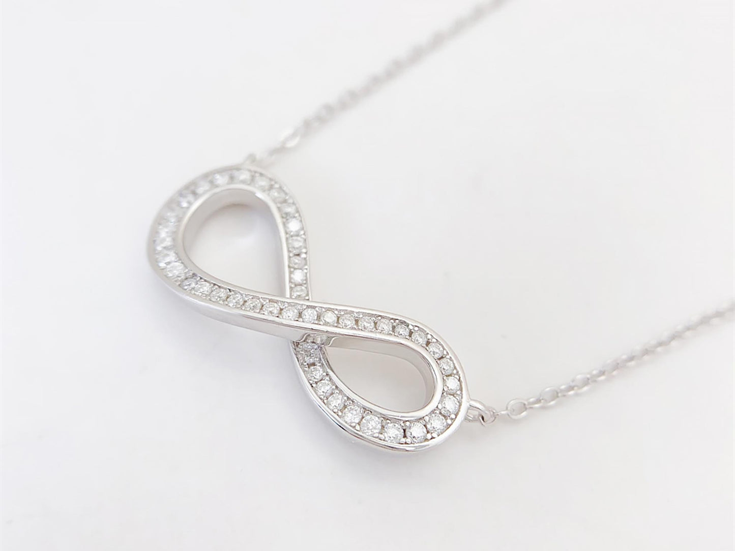 Witte ketting met infinity hanger rond gezet met briljanten