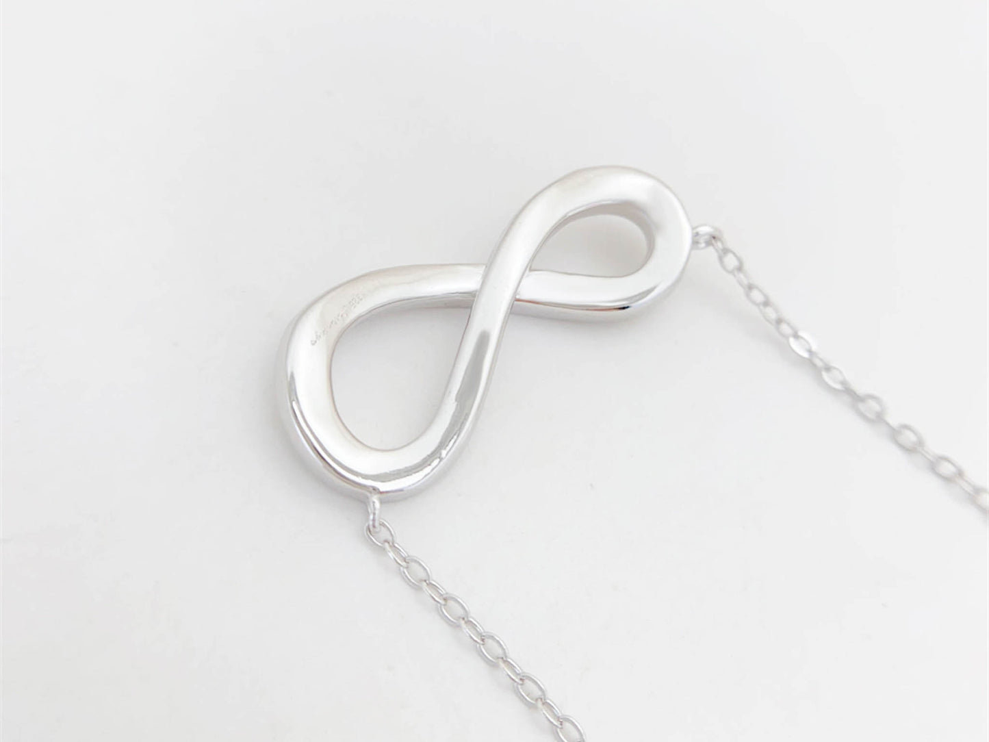 Witte ketting met infinity hanger rond gezet met briljanten