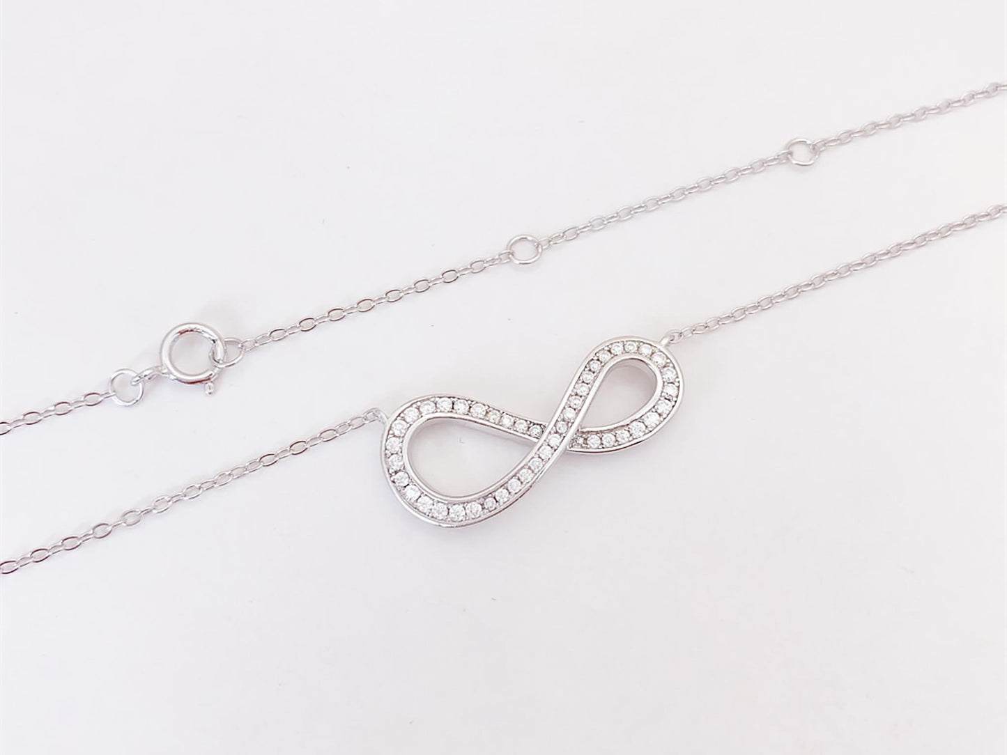 Witte ketting met infinity hanger rond gezet met briljanten