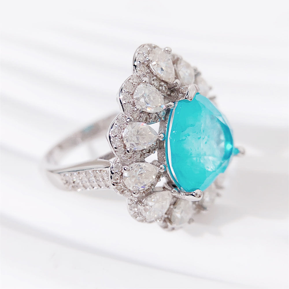Entourage ring met een grote sky blue hartvorm briljant, kleine briljant en druppelvorm briljanten