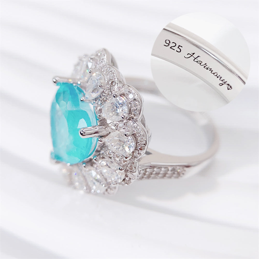 Entourage ring met een grote sky blue hartvorm briljant, kleine briljant en druppelvorm briljanten