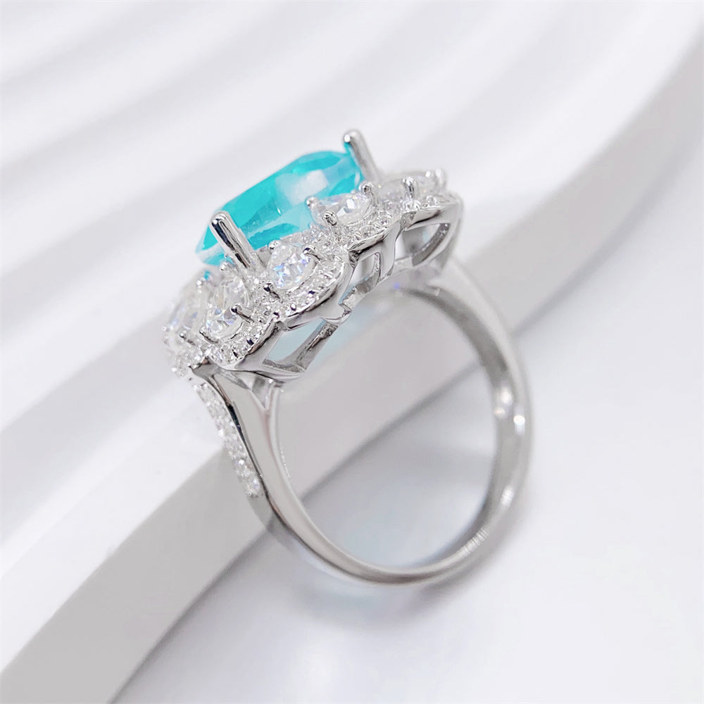 Entourage ring met een grote sky blue hartvorm briljant, kleine briljant en druppelvorm briljanten