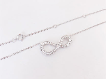 Witte ketting met infinity hanger rond gezet met briljanten