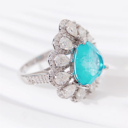 Entourage ring met een grote sky blue hartvorm briljant, kleine briljant en druppelvorm briljanten
