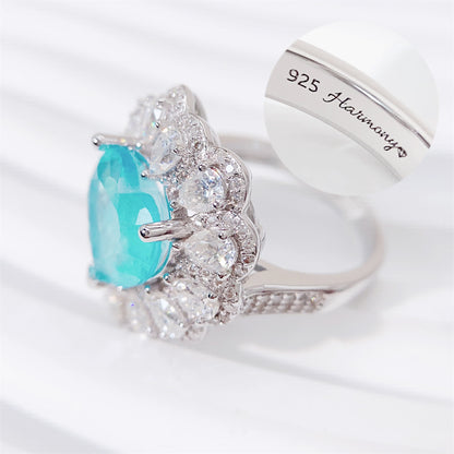 Entourage ring met een grote sky blue hartvorm briljant, kleine briljant en druppelvorm briljanten